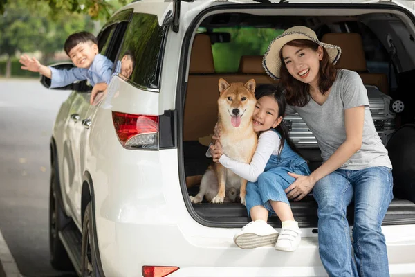 Asyalı bir aile annesi, annesi ve kızı Shiba 'nın köpeğiyle birlikte beyaz MPV' de oturuyorlar.