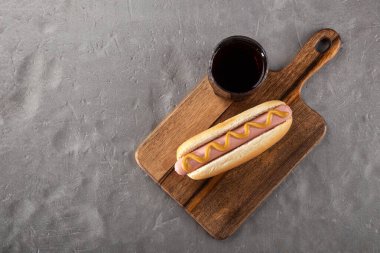 Tahtada hardallı sosisli sandviç. Sosisli sandviçler taş bir masada kola ile servis edilir. Metin için boş alan