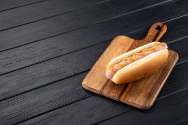 Tahtada hardallı sosisli sandviç. Sosisli sandviçler siyah masada servis edilir. Metin için boş alan