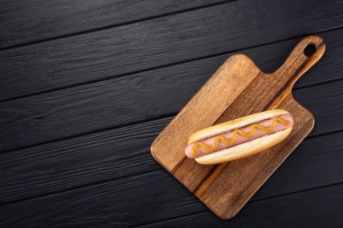 Tahtada hardallı sosisli sandviç. Sosisli sandviçler siyah masada servis edilir. Metin için boş alan