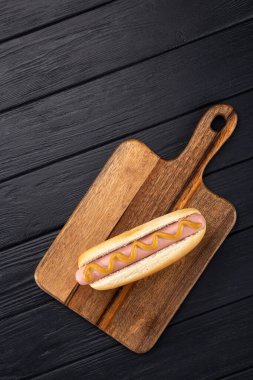 Tahtada hardallı sosisli sandviç. Sosisli sandviçler siyah masada servis edilir. Metin için boş alan