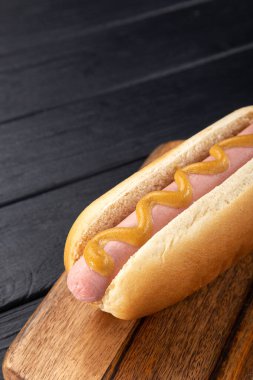 Tahtada hardallı sosisli sandviç. Sosisli sandviçler siyah masada servis edilir. Metin için boş alan