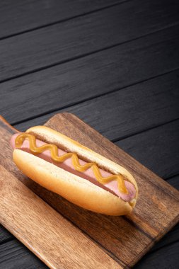 Tahtada hardallı sosisli sandviç. Sosisli sandviçler siyah masada servis edilir. Metin için boş alan