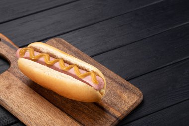 Tahtada hardallı sosisli sandviç. Sosisli sandviçler siyah masada servis edilir. Metin için boş alan