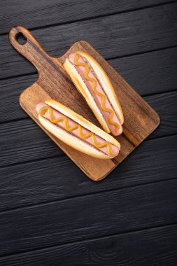 Tahtada hardallı sosisli sandviç. Sosisli sandviçler siyah masada servis edilir. Metin için boş alan