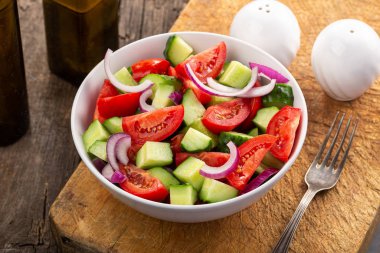Tabakta salatalık ve domates salatası ve ahşap masada sebze salatası.