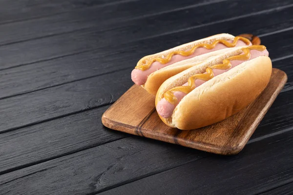 Hot Dogi Musztardą Drewnianej Desce Hot Dogi Serwowane Czarnym Stole — Zdjęcie stockowe
