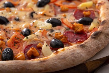 Masada taze pizza var. Lezzetli pizza. Domuz pastırmalı, sosisli, salamlı, pepperonili ve zeytinli büyük boy etli pizza. Akşam yemeği için ahşap masada ev yapımı lezzetli İtalyan pizzası. İtalyan mutfağı.