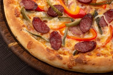 Masada taze pizza var. Lezzetli pizza. Domuz pastırmalı, sosisli, salamlı, pepperonili ve zeytinli büyük boy etli pizza. Akşam yemeği için ahşap masada ev yapımı lezzetli İtalyan pizzası. İtalyan mutfağı.