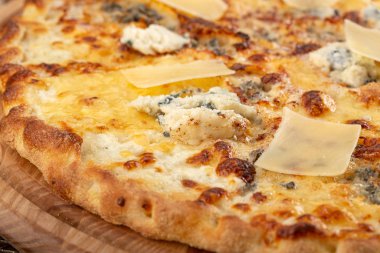 Masada taze pizza var. Lezzetli pizza. Çedar peynirli, parmesanlı, mozzarella peynirli ve domates soslu. Akşam yemeği için ahşap masada ev yapımı lezzetli İtalyan pizzası. İtalyan mutfağı.