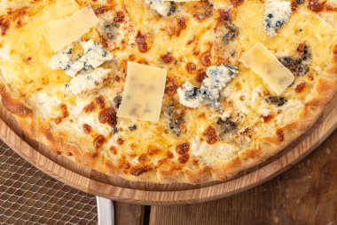 Masada taze pizza var. Lezzetli pizza. Çedar peynirli, parmesanlı, mozzarella peynirli ve domates soslu. Akşam yemeği için ahşap masada ev yapımı lezzetli İtalyan pizzası. İtalyan mutfağı.