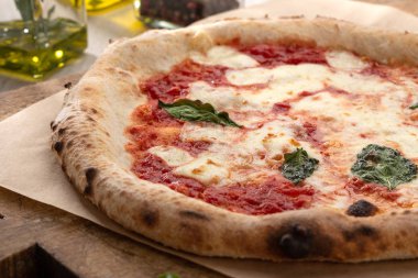 Masada taze pizza var. Kıyma peyniriyle sade pizza, üstüne fesleğen. Et ve fesleğenli pizza. Akşam yemeği için ahşap masada ev yapımı lezzetli İtalyan pizzası. İtalyan mutfağı.