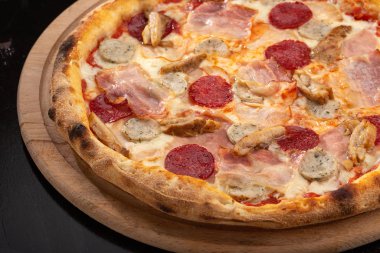 Masada taze pizza var. Lezzetli pizza. Domuz pastırmalı, sosisli, salamlı, pepperonili ve zeytinli büyük boy etli pizza. Akşam yemeği için ahşap masada ev yapımı lezzetli İtalyan pizzası. İtalyan mutfağı.