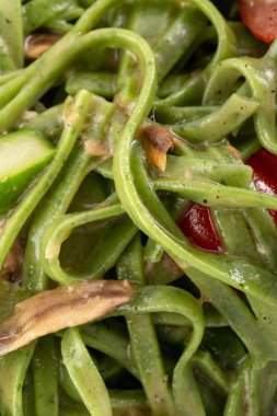 Geleneksel İtalyan makarnası. Masada fesleğenli ve ançüezli yeşil ıspanaklı tagliatelle makarna. İtalyan deniz ürünleri. Akşam yemeği için ahşap masada ev yapımı İtalyan geleneksel makarnası. İtalyan mutfağı..