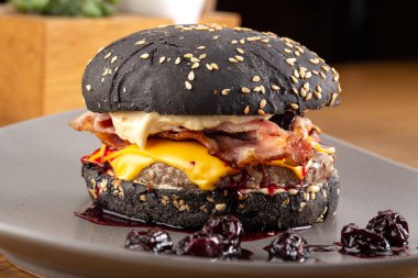 Tahta masada sulu pastırmalı burger. Lezzetli fast food ızgara taze lezzetli burger. Sığır eti, domates, peynir, pastırma ve marullu ev yapımı leziz ızgara burger. Kızarmış hamburger ve farklı soslar..