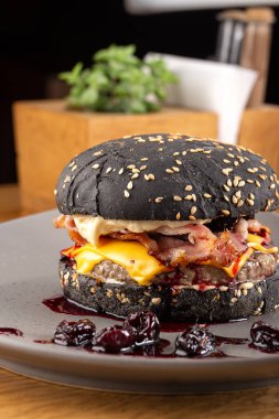 Tahta masada sulu pastırmalı burger. Lezzetli fast food ızgara taze lezzetli burger. Sığır eti, domates, peynir, pastırma ve marullu ev yapımı leziz ızgara burger. Kızarmış hamburger ve farklı soslar..