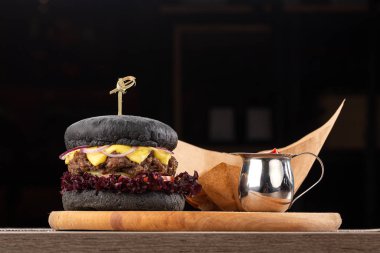 Tahta masada sulu pastırmalı burger. Lezzetli fast food ızgara taze lezzetli burger. Sığır eti, domates, peynir, pastırma ve marullu ev yapımı leziz ızgara burger. Kızarmış hamburger ve farklı soslar..