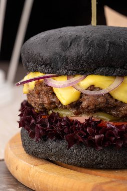 Tahta masada sulu pastırmalı burger. Lezzetli fast food ızgara taze lezzetli burger. Sığır eti, domates, peynir, pastırma ve marullu ev yapımı leziz ızgara burger. Kızarmış hamburger ve farklı soslar..