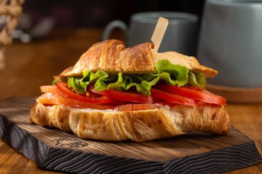 Füme tuzlu somon, domates, ıspanak ve roka ile kruvasan. Tahta tahtada servis edilen kruvasan sandviçleri. Yumurtalı kruvasan, erimiş peynir, maydanoz, tavuk jambon, füme somon..