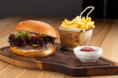 Tahta masada sulu pastırmalı burger. Lezzetli fast food ızgara taze lezzetli burger. Sığır eti, domates, peynir, pastırma ve marullu ev yapımı leziz ızgara burger. Kızarmış hamburger ve farklı soslar..