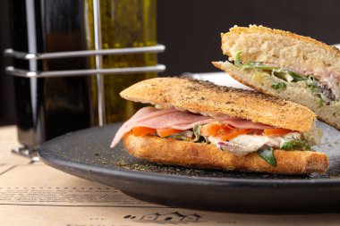 Tahta masada sulu bir sandviç. Lezzetli fast food ızgara taze lezzetli sandviç. Lezzetli ev yapımı et, domates, peynir, pastırma ve marullu sandviç. Patates kızartmalı sandviç ve farklı soslar..