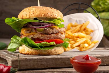 Tahta masada sulu pastırmalı burger. Lezzetli fast food ızgara taze lezzetli burger. Sığır eti, domates, peynir, pastırma ve marullu ev yapımı leziz ızgara burger. Kızarmış hamburger ve farklı soslar..