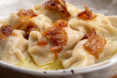 Pierogi, karamelli tuzlu soğanla servis edilen hamur tatlısı. Geleneksel Polonya yemeği - pierogi veya etli börek, patates, mantar, ekşi krema ve kızarmış soğan