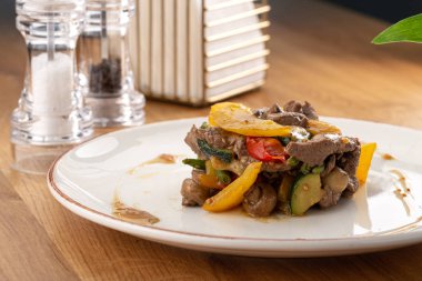 Lezzetli taze salata. Dana etli salata, domates, biber, salatalık ve mantarlı ahşap zemin. Restoran yemekleri, kapatın. Et salatası. Salatayı sıcak dana etiyle kapatın..