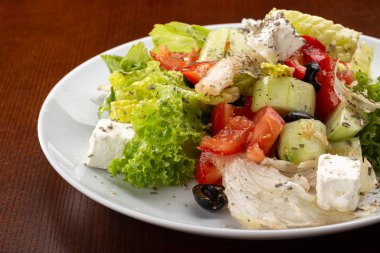 Lezzetli taze salata. Beyaz peynirli Yunan salatası, organik zeytin, sulu domates, kırmızı biber, kırmızı soğan, salatalık ve marul. Taze sebzeli Yunan salatası. Salata 'nın yakın görüntüsü. Sağlıklı, diyet lezzetli yaz yemekleri.