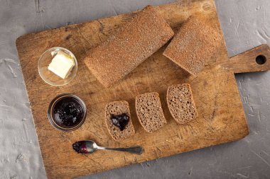 Tereyağlı taze ekmek, masada reçel. Kahvaltı. Tereyağlı ekmek dilimi, ahşap masada reçel