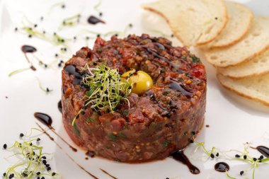 Taze sığır etli tartar, ekmek, yumurta ve beyaz tabakta mikro yeşil. Dana etli tartar.
