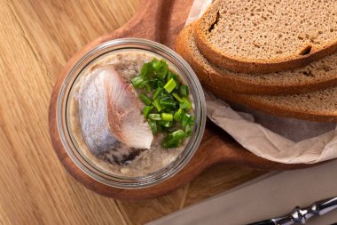 Restoranda masada ringa balığı. Dereotu ve doğranmış soğanlı salamura ringa filetosu. Ekmek dilimleri ve kırmızı soğanlı ringa balığı.