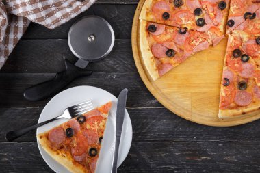 Lezzetli pizza. Domuz pastırmalı, sosisli, salamlı, pepperonili ve zeytinli büyük boy etli pizza. Akşam yemeği için ahşap masada ev yapımı lezzetli İtalyan pizzası. İtalyan mutfağı.