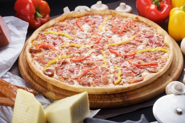 Lezzetli pizza. Domuz pastırmalı, sosisli, salamlı, pepperonili ve zeytinli büyük boy etli pizza. Akşam yemeği için ahşap masada ev yapımı lezzetli İtalyan pizzası. İtalyan mutfağı.