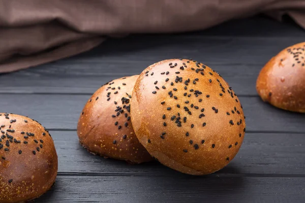 Delicious fresh round buns with sesame seeds on a board. Homemade whole wheat burger buns with sesame seeds on wooden background.