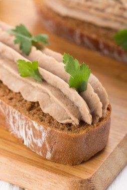 Beyaz bir masada etli börek var. Beyaz masa üzerinde ciğer ezmesi ve bitkilerle Kanepe mini sandviç.