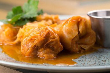 Lahana ruloları kıyma ve pirinçle doldurulmuş ve eski bir kırsal masada servis edilmiş. Doldurulmuş lahana yaprakları kıyma ve domates soslu pirinç..