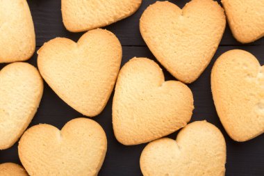 Kalp şeklinde kurabiyeler, Sevgililer Günü için süslenmiş. Metin için boş alan. Siyah ahşap bir masada reçelli iki kalp şeklinde kurabiye. Siyah ahşap bir masanın üzerinde kalp şeklinde kurabiyeler olan tahta bir tabak. Kartpostal gibi. Kurabiyeli arkaplan