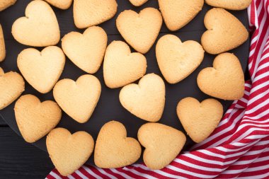 Kalp şeklinde kurabiyeler, Sevgililer Günü için süslenmiş. Metin için boş alan. Siyah ahşap bir masada reçelli iki kalp şeklinde kurabiye. Siyah ahşap bir masanın üzerinde kalp şeklinde kurabiyeler olan tahta bir tabak. Kartpostal gibi. Kurabiyeli arkaplan