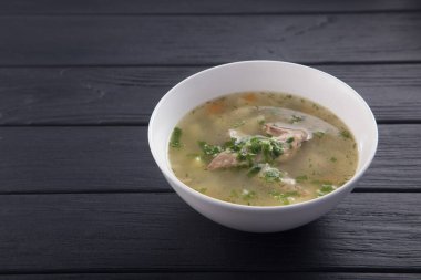 Bir kase tavuk çorbası ve ekmek. Siyah ahşap bir masada beyaz tabakta tavuk çorbası. Tavuklu erişte. Bakso, erişteli köfte çorbası. Metin için boş alan. 