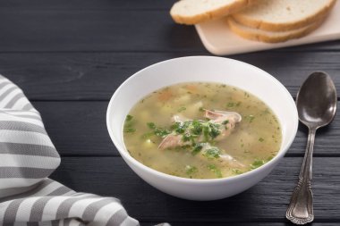 Bir kase tavuk çorbası ve ekmek. Siyah ahşap bir masada beyaz tabakta tavuk çorbası. Tavuklu erişte. Bakso, erişteli köfte çorbası. Metin için boş alan. 