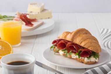 Beyaz ahşap masada jambon, peynir ve roka ile taze kruvasan sandviçi. Kruvasan kahvaltısı. Taze Fransız kruvasanı. Metin için boş alan. Yukarıdan bak. Üst görünüm.