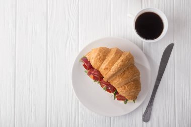 Beyaz ahşap masada jambon, peynir ve roka ile taze kruvasan sandviçi. Kahve, peynir, jambon, portakal suyu ve reçelle servis edilir. Taze Fransız kruvasanı. Metin için boş alan. Yukarıdan bak. Üst görünüm.