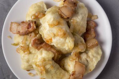 Pierogi, karamelli tuzlu soğanla servis edilen hamur tatlısı. Geleneksel Polonya yemeği - pierogi veya etli börek, patates, mantar, ekşi krema ve kızarmış soğan. Kapatın, mesaj için yer açın. Yukarıdan görüntüle.