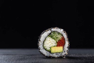 Sebzeli suşi dürümü ve karanlık bir arka plan. Suşi taştan bir tabakta ve koyu betondan bir arka planda. Suşi seti ve yemek çubukları. Taze Japon mutfağı. Asya yemeği. Menü için suşi resmi. Kapat.