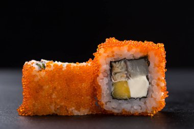 Suşi seti. Maski, gunkan ve suşi ruloları taş levhada servis edilir. Suşi taştan bir tabakta ve koyu betondan bir arka planda. Suşi seti ve yemek çubukları. Taze Japon mutfağı. Asya yemeği. Menü için suşi resmi. Kapat.