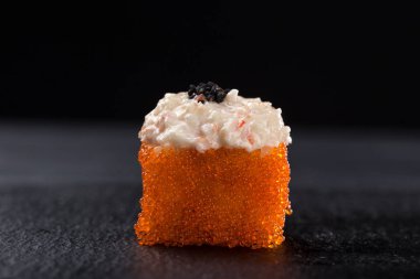 Gunkanlar arka planda baharatlı somon balığı. Gunkan suşisine baharatlı sosla yakından bak. Taze Japon mutfağı. Asya yemeği. Menü için suşi resmi. Suşi, siyah bir tabağa kurulmuş, karanlıkta izole edilmiş. 