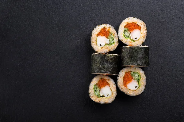 Sushi Rolls with shrimp on a dark background. Japanese traditional roll with prawn. Sushi set on a stone plate and dark concrete background. Sushi roll set and chopsticks. Fresh Japanese cuisine. asian food. Sushi image for menu. close up