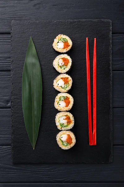 Sushi Rolls with shrimp on a dark background. Japanese traditional roll with prawn. Sushi set on a stone plate and dark concrete background. Sushi roll set and chopsticks. Fresh Japanese cuisine. asian food. Sushi image for menu. close up