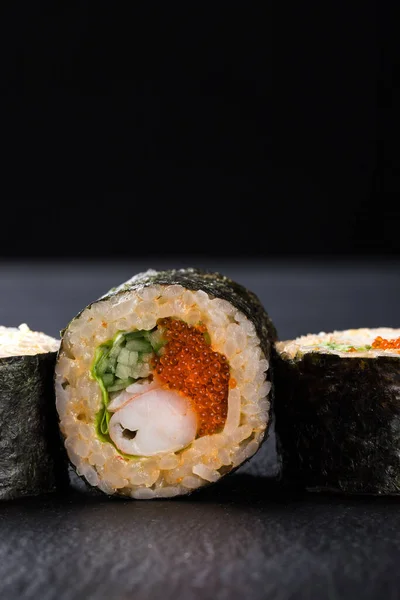 Sushi Rolls with shrimp on a dark background. Japanese traditional roll with prawn. Sushi set on a stone plate and dark concrete background. Sushi roll set and chopsticks. Fresh Japanese cuisine. asian food. Sushi image for menu. close up